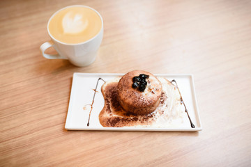 A dessert and a cup of coffee on the wooden table.