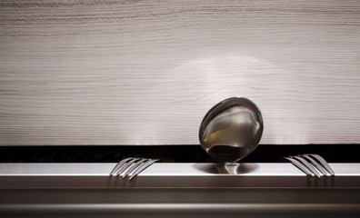 Spoon and two forks lean out of a drawer.