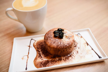 A dessert and a cup of coffee on the wooden table.