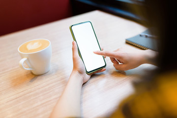 Woman using phone on the table in cafe.