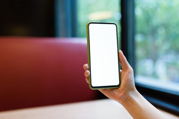 Cropped hands of woman's hand using smart phone in cafe.