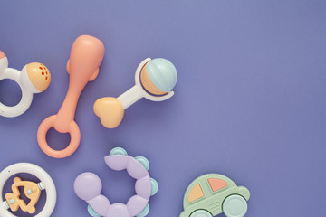 Flat lay composition with baby rattles set in pastel colors and space for text on lilac background.