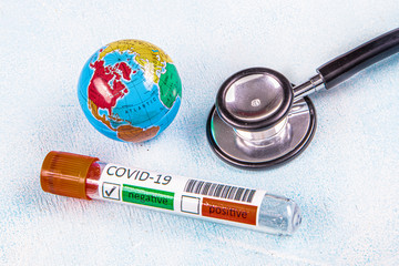 Coronavirus updates text with stethoscope, world globe and blood sample vacuum tube on blue...