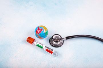 Coronavirus updates text with stethoscope, world globe and blood sample vacuum tube on blue...
