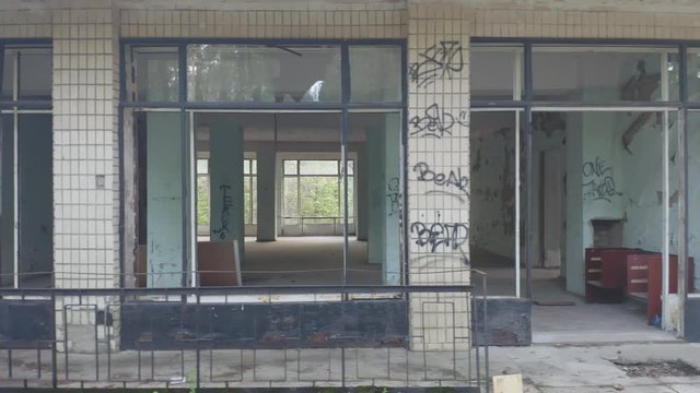 Abandoned building exterior with broken windows. Aerial side view. Low angle shot