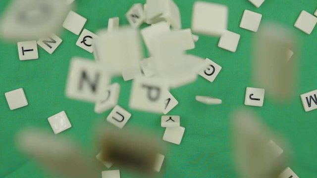 Random Alphabet Scrabbles falling down to green background . alphabet dropping on green table