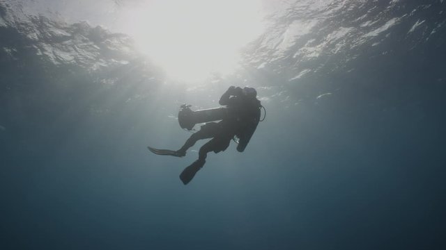 Rebreather diver on a decompression stop backlit by the sun