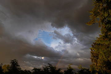 Fototapeta na wymiar Dramatic sky with dark rain clouds and a rainbow