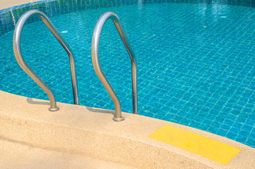 A metal grab bars ladder in hotel swimming pool. Swimming pool designed to hold water for leisure activities or enable swimming.