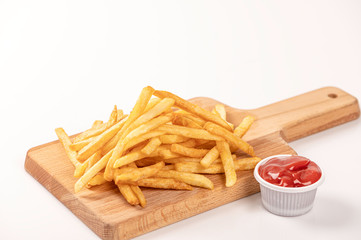 French fries and ketchup  on cutting board on white background.