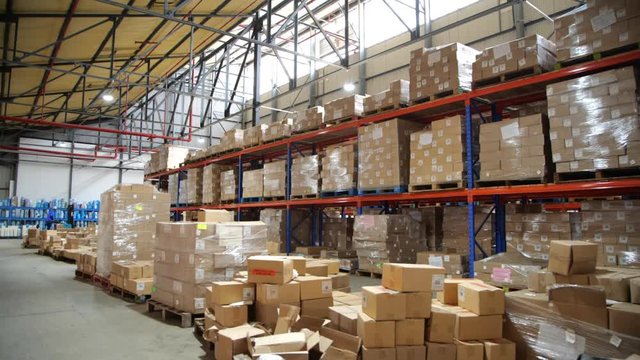 Big warehouse, storage hall with rows and racks holding carton boxes and parcels on pallets