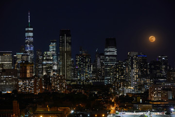 Fototapeta na wymiar A full moon and night sky over a downtown city skyline.