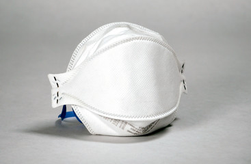 An N95 medical face mask for use to protect against contamination of respiratory infection, commonly used to protect agains the spread of COVID-19 virus, set against a plain white background.