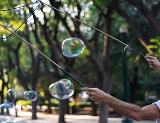 Man arms holding sticks making huge soap bubbles