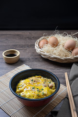 Oyako-don rice bowl topped with chicken, onions and egg cooked with special sauce. oyakodonburi Japanese food on wooden background.
