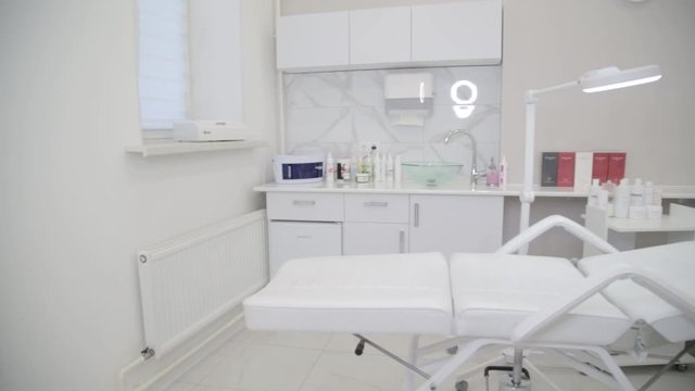 Medical Center. Beauty saloon. White daybed for beauty treatments in the center of the room. Close-up. Bright clean room. A large mirror on the wall. Stylish interior.