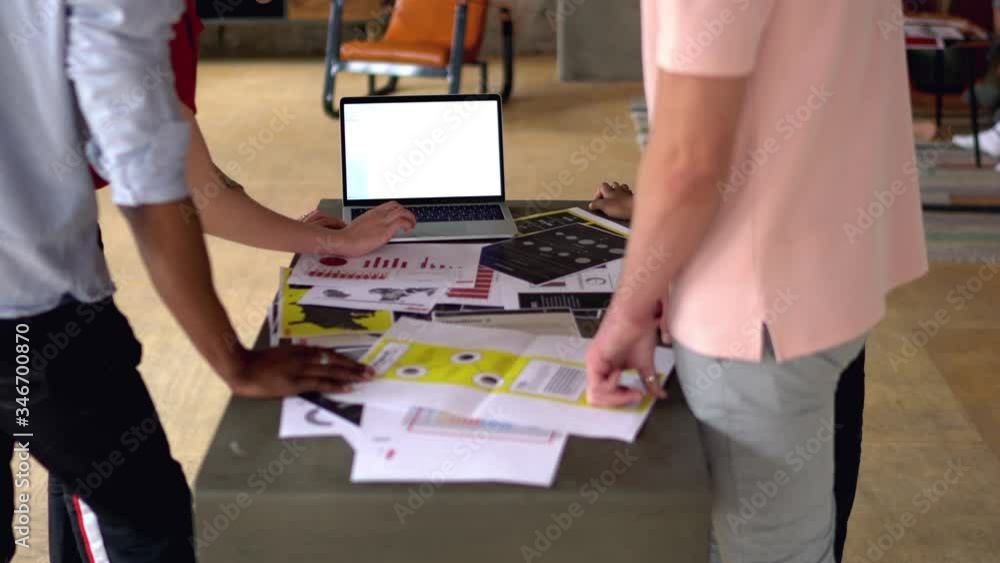 Poster multicultural young people collaborating with each other on design project standing at one table wit