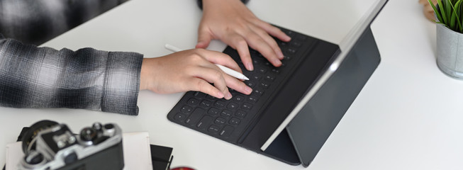 Cropped shot of female graphic designer typing on digital tablet on worktable