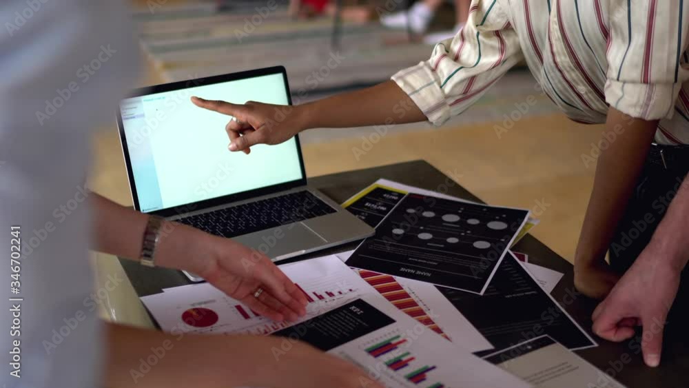 Poster casual dressed diverse young people collaborating on studying task standing at one table with laptop