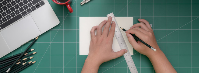 Overhead shot of student cutting paper with cutter on cutting mat