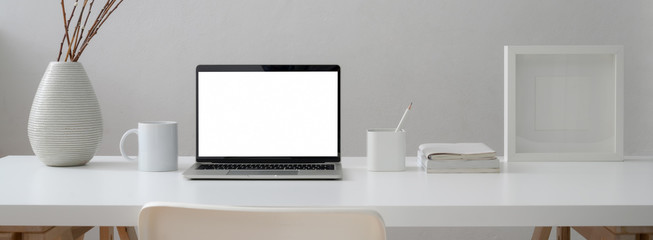 Close up view of minimal worktable with mock-up laptop, mug, supplies and decoration with chair