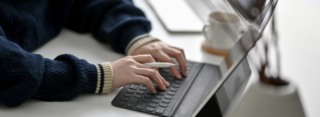 Cropped shot of female freelancer typing on digital tablet on white worktable