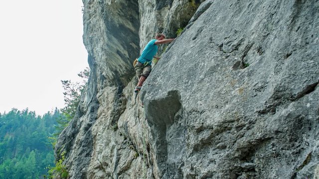 young man pro rock climber ascend a vertical cliff. Risk and challenge lover