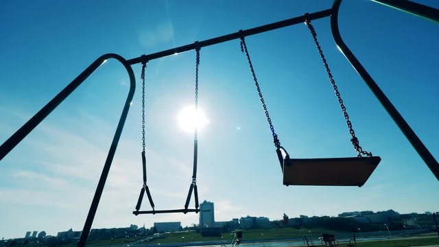 The sun shining through the swings in motion. Covid-19 outbreak, coronavirus lockdown concept.