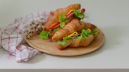 Close up view of croissant sandwiches with ham and cheese on wooden plate