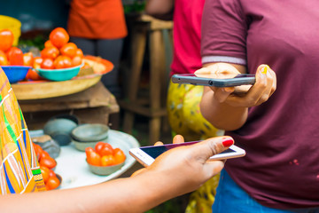 African market women doing wireless transfer with their smart phone . woman paying Bills online mobile phone using bar code scanner