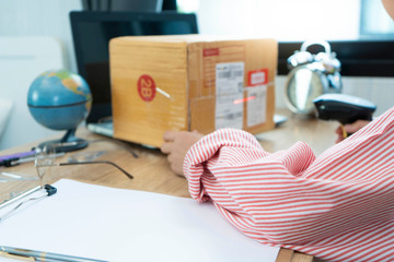 ecommerce concept, Online shopping concept. Woman wearing red shirt in office or home working prepare product in the box for send to customer who order by online. box for logistic with barcode scanner
