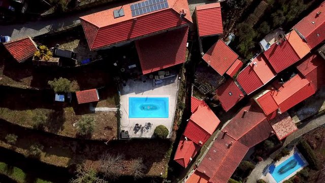 Drone lifting up from covered swimming pool in Portuguese villa backyard to reveal neighboring houses & gardens
