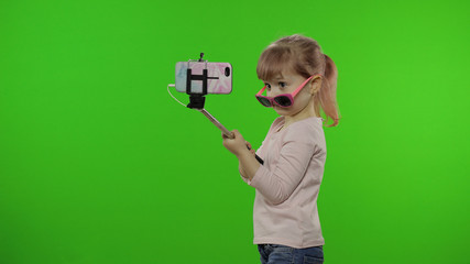 Girl child makes selfie, blogging on mobile phone using selfie stick. Chroma key