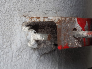 Rusty and dirty bolt installing in cement wall for holding the iron pillar or metal  equipment. Connecting or joining part of construction.