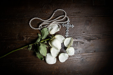 A wilted rose on a distressed wooden tabletop with other items