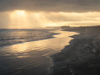 sun rays poking through clouds over ocean beach