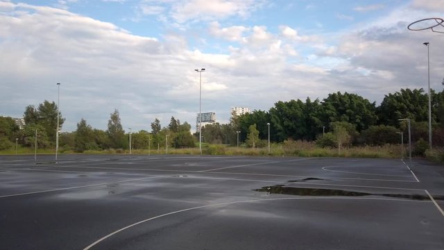 Empty wet netball field on a rainy day in the middle of a community park. Slow panning to the right.