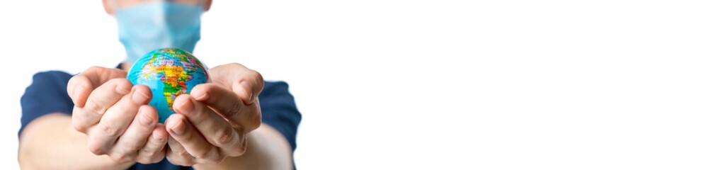 Banner. Close-up of a man's hands holding a small globe, with images Africa,   a man in a medical mask out of focus, dressed in a blue t-shirt,  on a white isolated background. Coronavirus, Covid-19