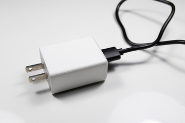 White charger adapter and black USB cable on a white background The concept of charging technology...