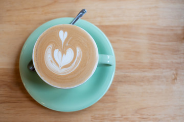 Cup of hot art cappuccino coffee on wooden table in cafe shop