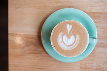 Cup of hot art cappuccino coffee on wooden table in cafe shop