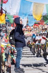 Young man traveler with sweater and backpack traveling in Shika snow mountain, happy Asian hiker enjoy in trip Zhongdian city ( Shangri-La) Yunnan, China. Explore, Asia and Solo travel concept