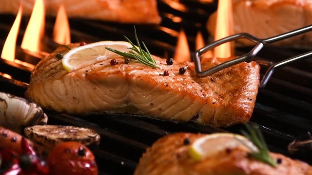 Grilled salmon fish with various vegetables on pan on the flaming grill