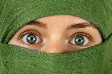 close up of green eyes of a girl with face wrapped in a green scarf