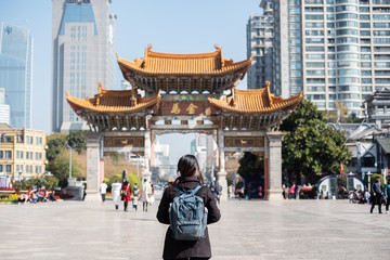 Young woman traveler traveling at Jinbi square, golden Horse and Jade Rooster Archways. landmark and popular for tourists attractions in Kunming, Yunnan, China. Asia and Solo travel concept