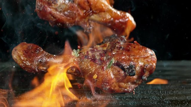 Close-up of falling raw tasty chicken legs on iron cast grate, super slow motion, filmed on high speed cinematic camera at 1000 fps.
