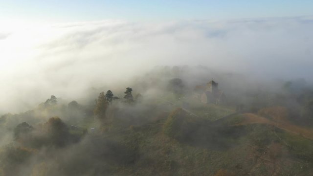 4k Aerial shot of a church in a foggy/cloudy forest on a mountain.