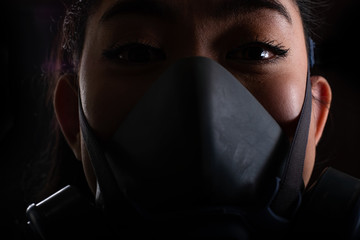 Close up the woman of young Asia woman putting on a Half-Mask replaceable particulate filter respirator to protect from airborne diseases as the chemical dust and smog