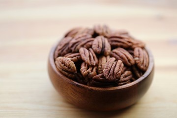 Pecan nuts close-up in a wooden  cup on a light wooden background.Healthy fats ingredient. Wholesome food and snack.Vegetarian and vegan food.