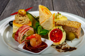 food platter with meat and cheese rolls and vegetables with sauces